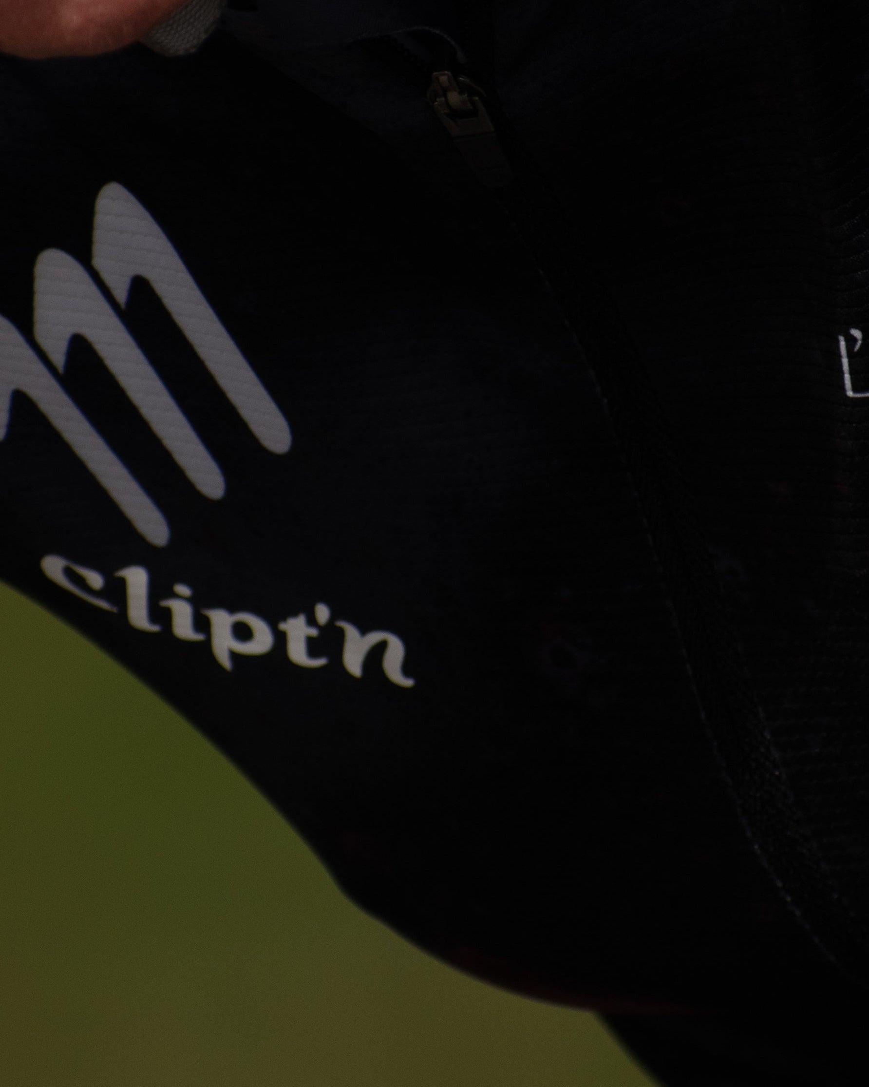 Close-up of a person wearing a black cycling outfit with 'Clipt'n' branding.