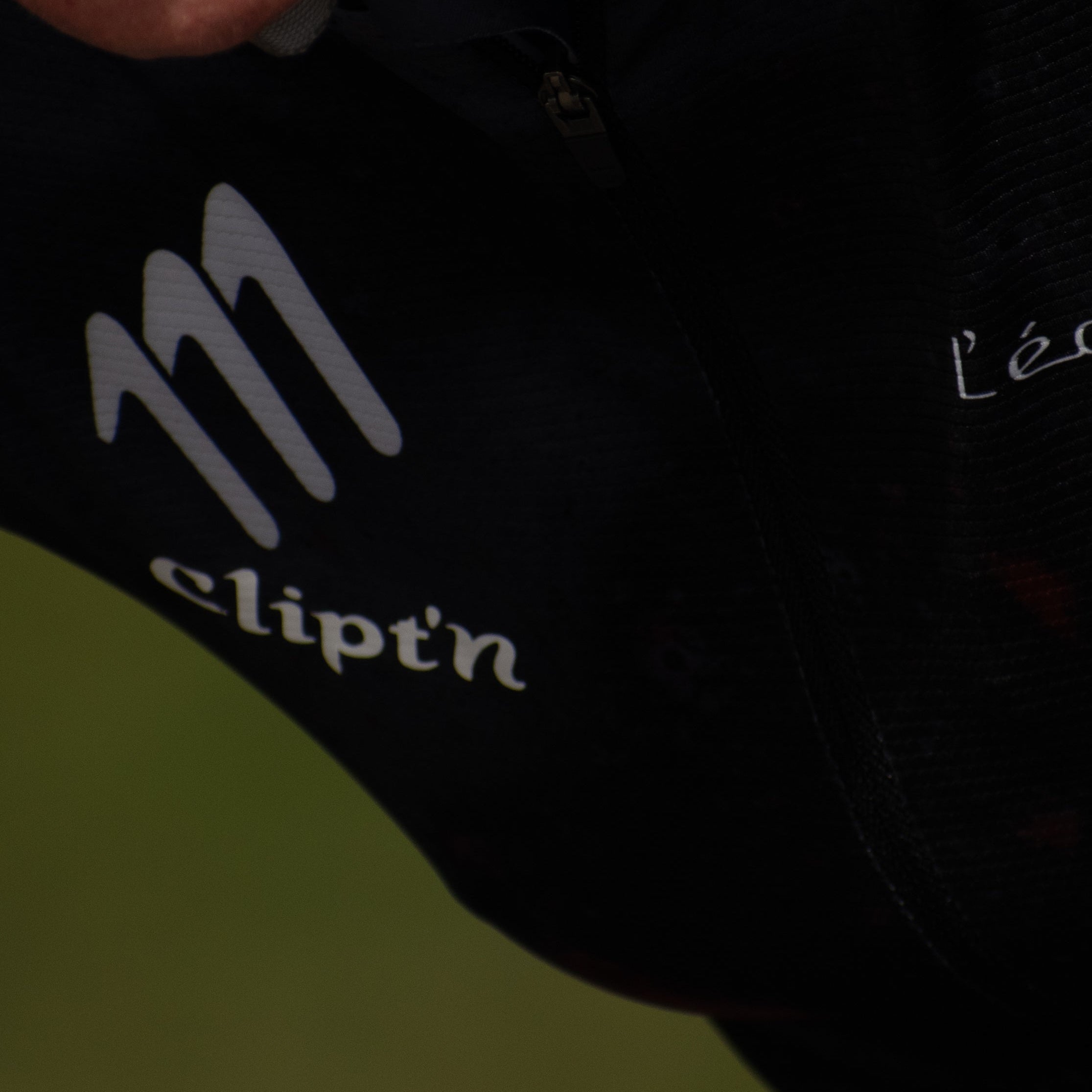Close-up of a person wearing a black cycling outfit with 'Clipt'n' branding.