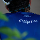 Person wearing a blue cycling jersey with 'Clipt'n' branding, looking over their shoulder.